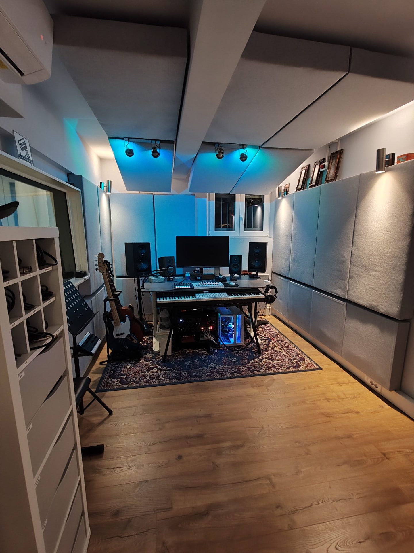 Postazione di produzione musicale con tastiere, monitor e chitarre in regia