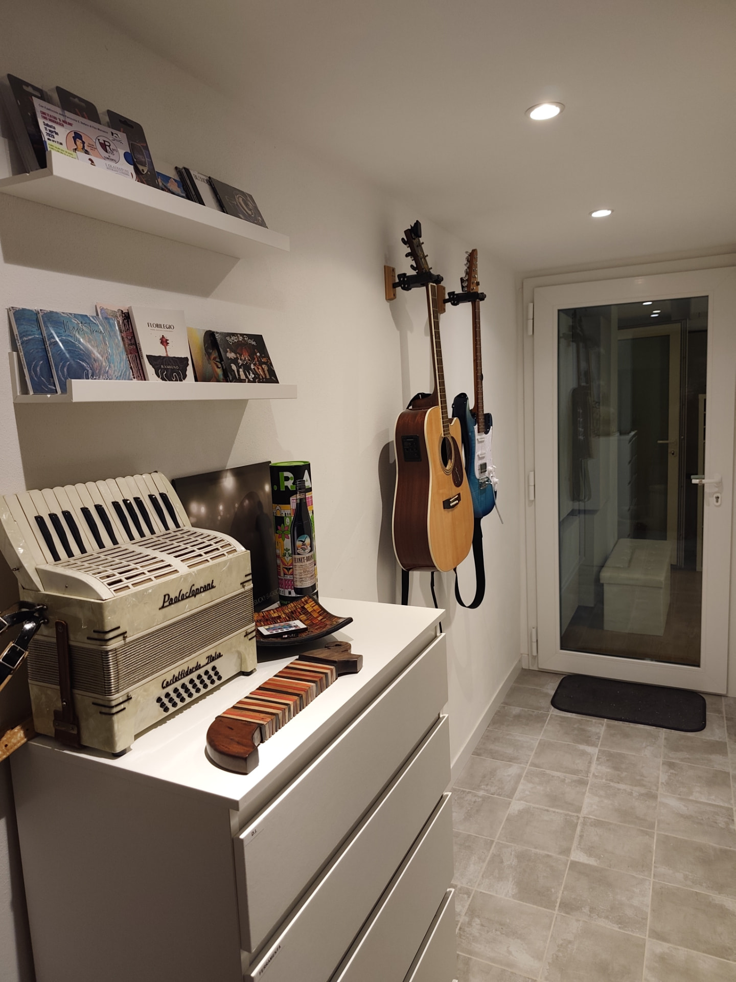 Corridoio dello studio con chitarre appese e accesso al booth